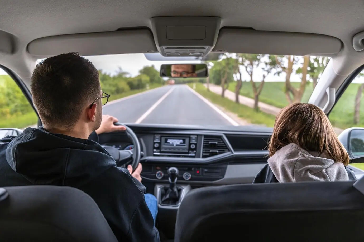 Вид из лобового стекла: водитель едет по весенней лесной дороге.